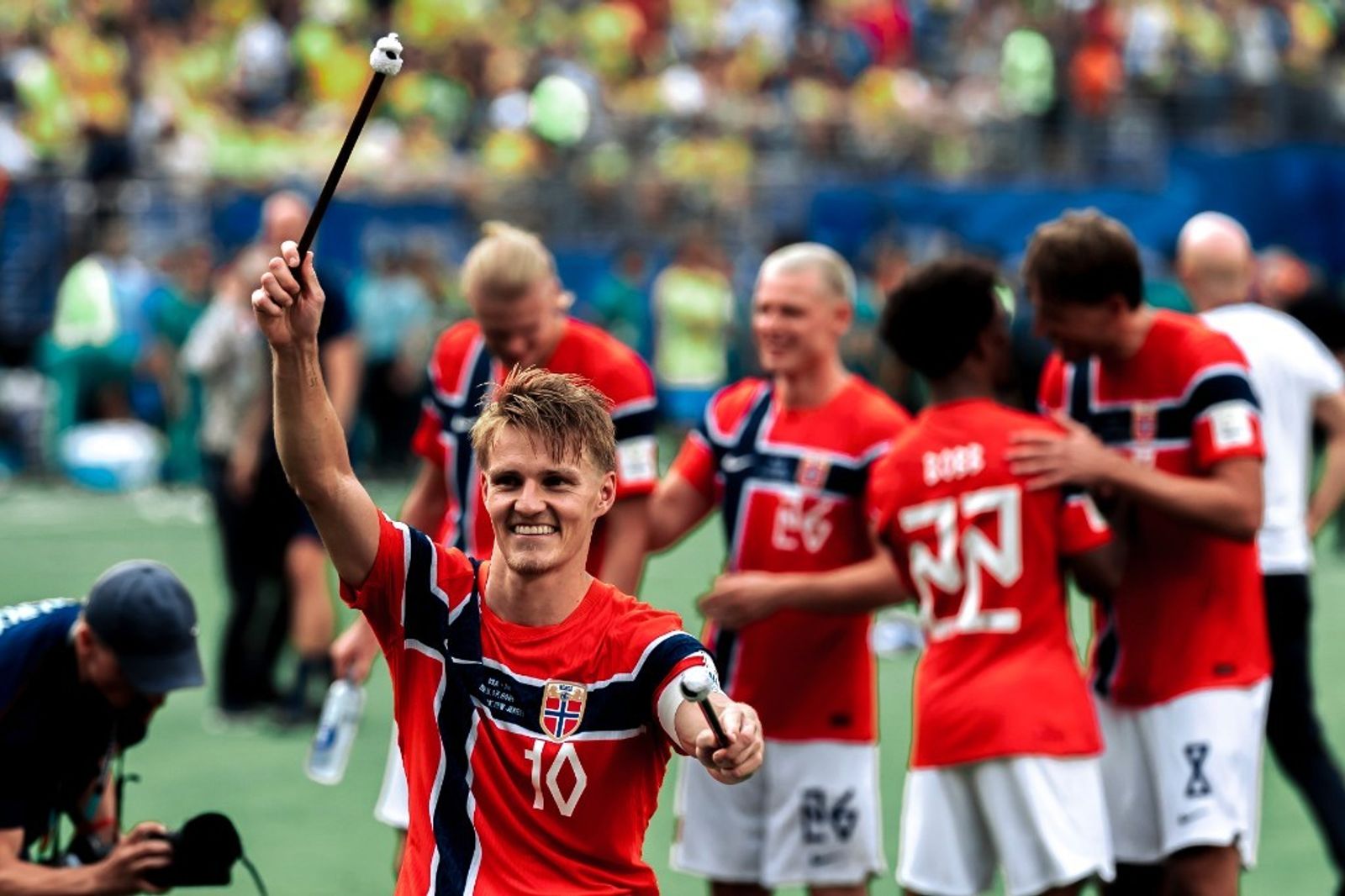 Martin Odegaard holds drum mallets while celebrating with Erling Haaland and Norway teammates after beating Brazil