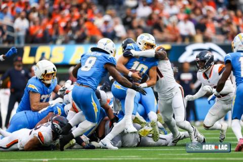 Denver Broncos defenders converge on Los Angeles Chargers quarterback Justin Herbert (10) in a pile at the line of scrimmage at SoFi Stadium.