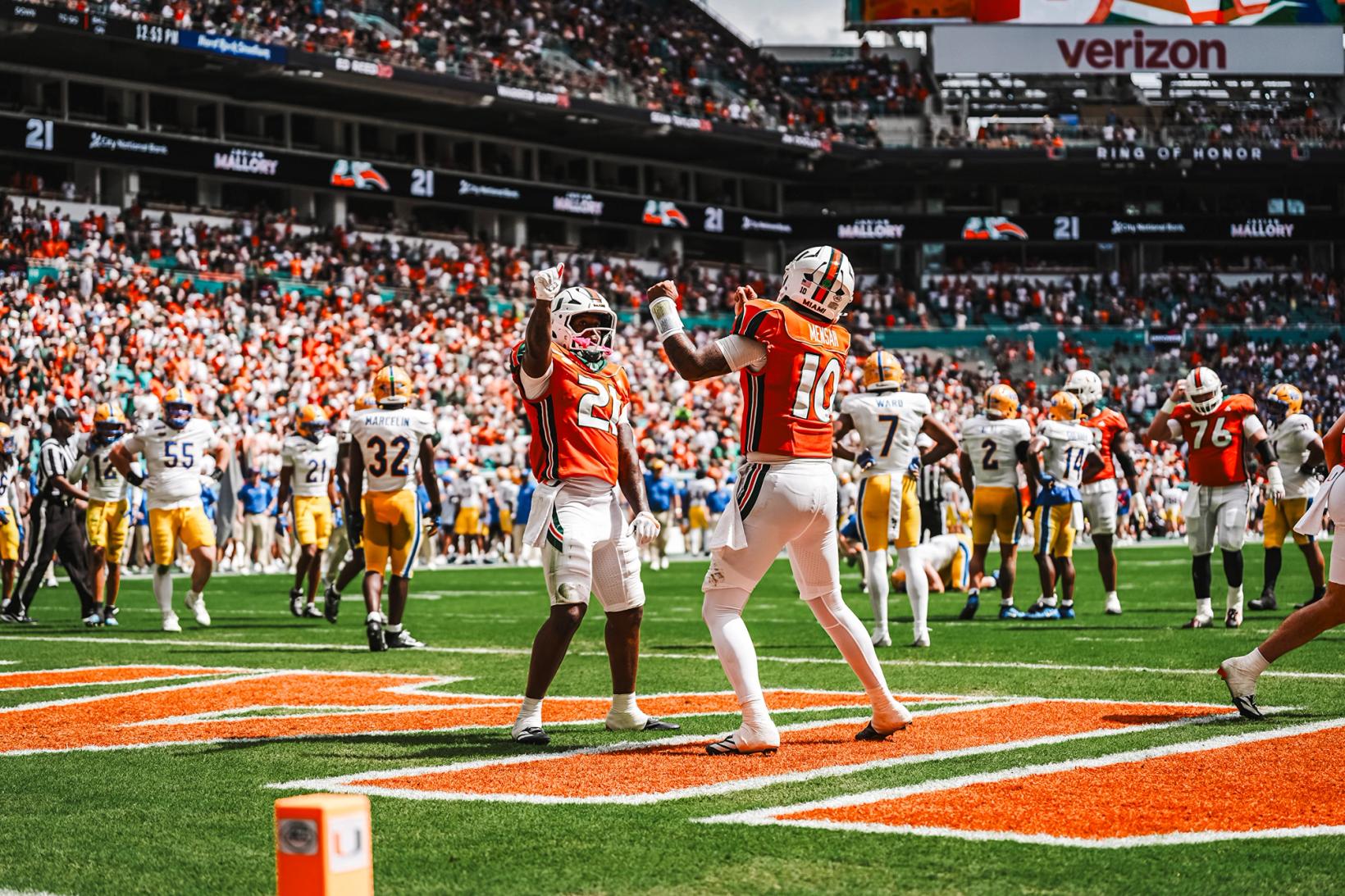 Miami quarterback Darian Mensah (10) and a teammate wearing No. 21 celebrate in the end zone in orange throwback jerseys during Miami's 52-23 win over Pitt at Hard Rock Stadium on Oct. 24, 2026