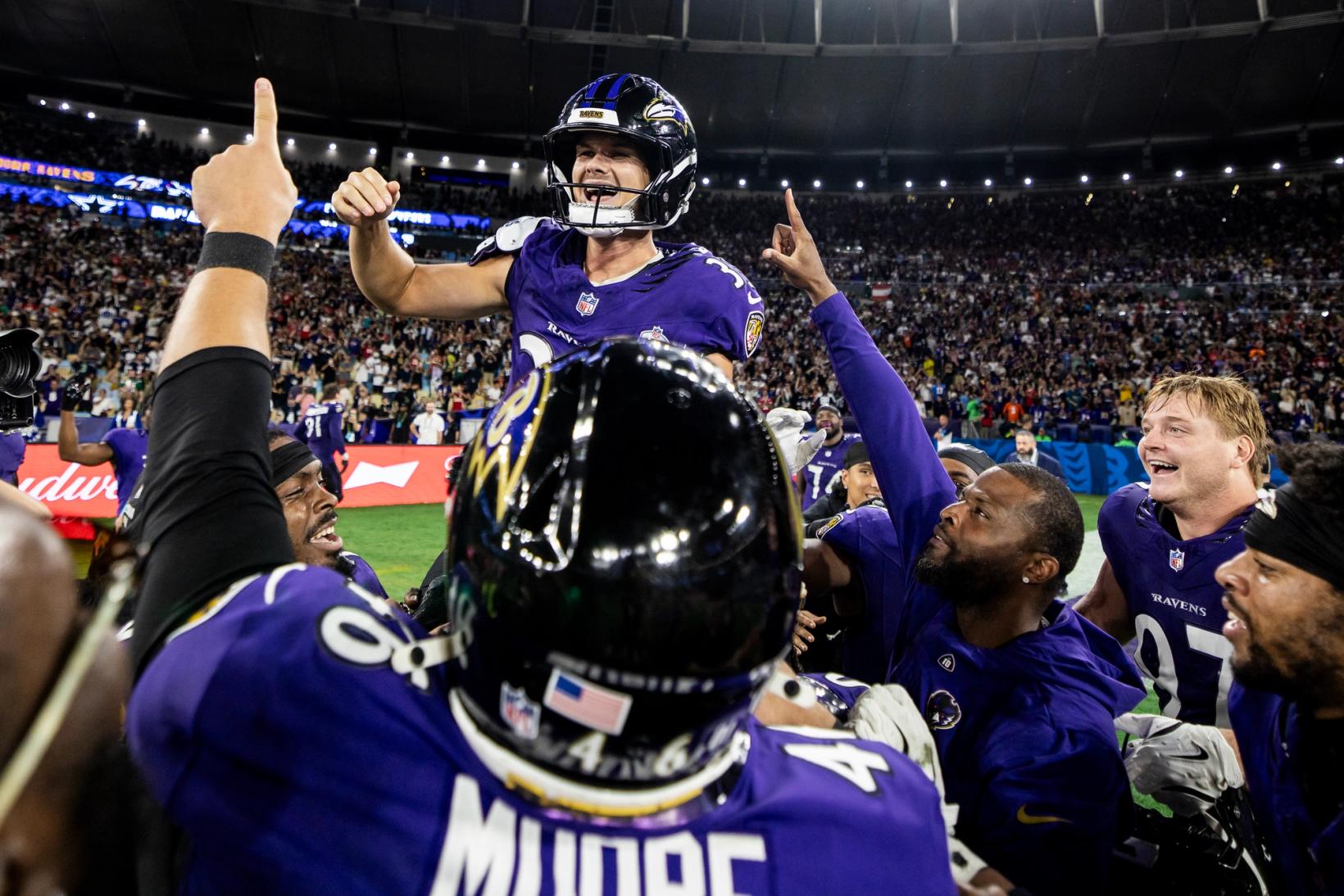 Baltimore Ravens players lift a celebrating teammate onto their shoulders on the field at Maracanã Stadium as a packed crowd looks on.