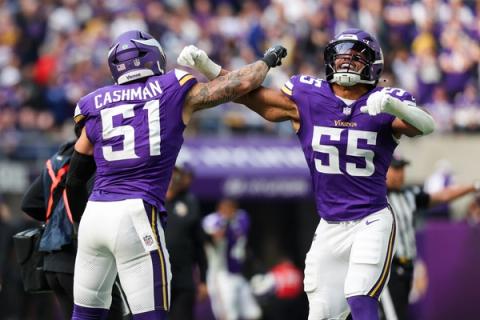 Minnesota Vikings linebacker Blake Cashman (51) and teammate No. 55 bump arms in celebration in front of a crowd dressed in purple.
