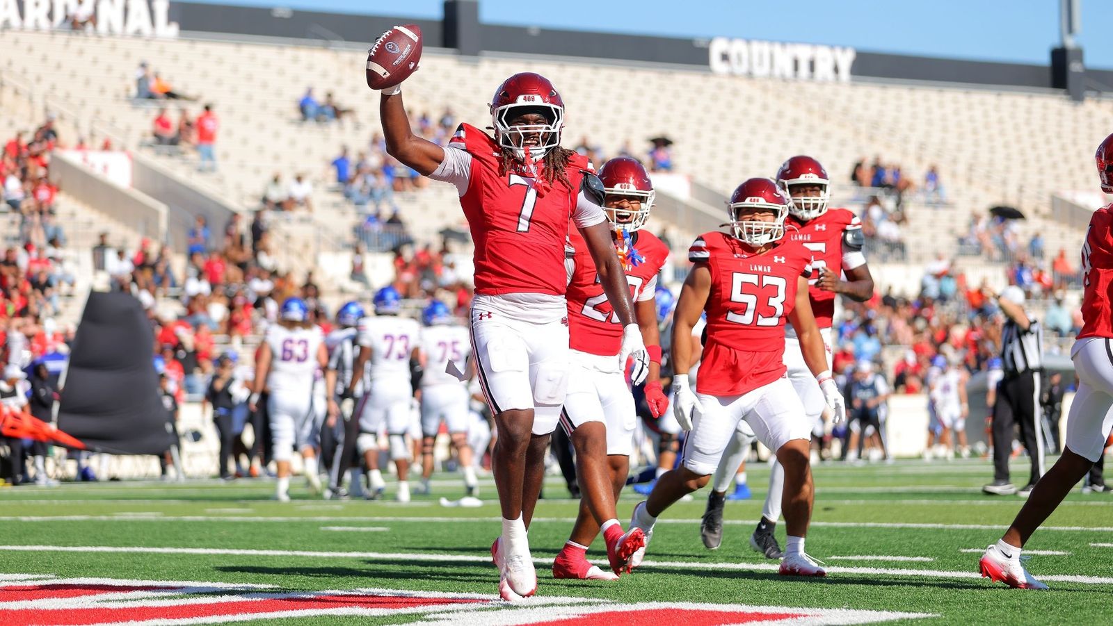 Lamar's Andrew Huff (7) holds the football aloft as Cardinals teammates celebrate at Provost Umphrey Stadium during Lamar's 35-10 Homecoming win over Houston Christian on Oct. 24, 2026