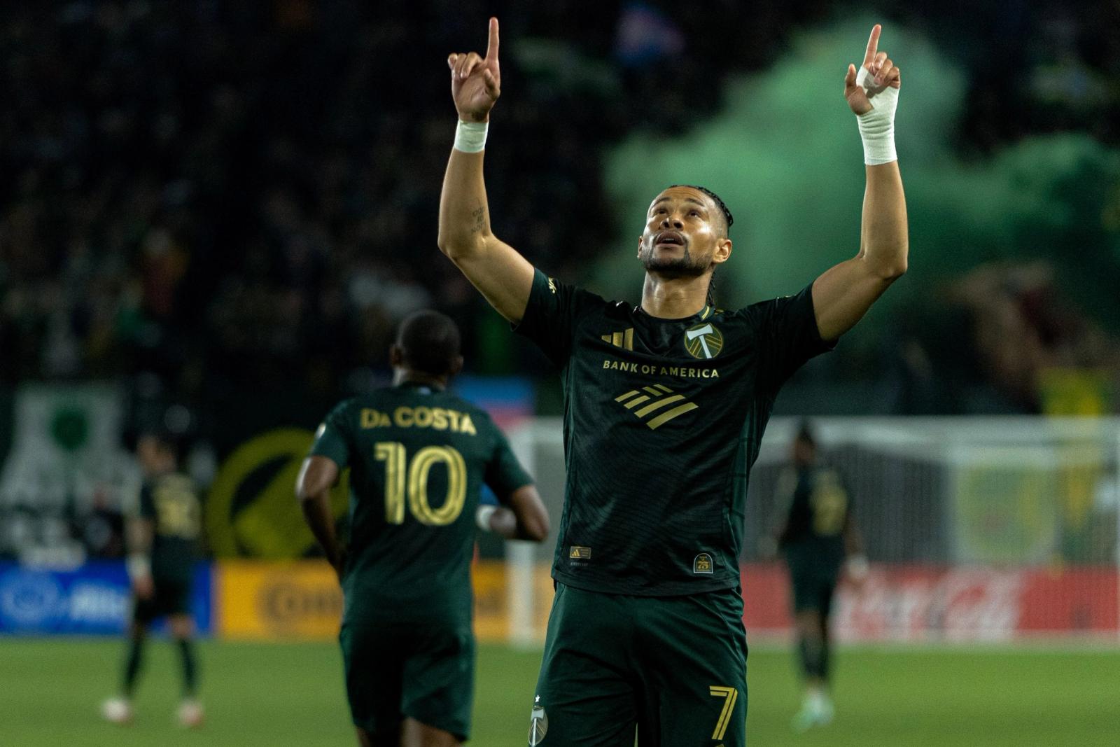 A Portland Timbers player points skyward in celebration as green smoke drifts behind him at Providence Park on October 24, 2026.