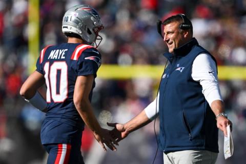 New England Patriots quarterback Drake Maye (10) slaps hands with a smiling Patriots coach wearing a headset on the sideline during the game against the New York Jets at Gillette Stadium.