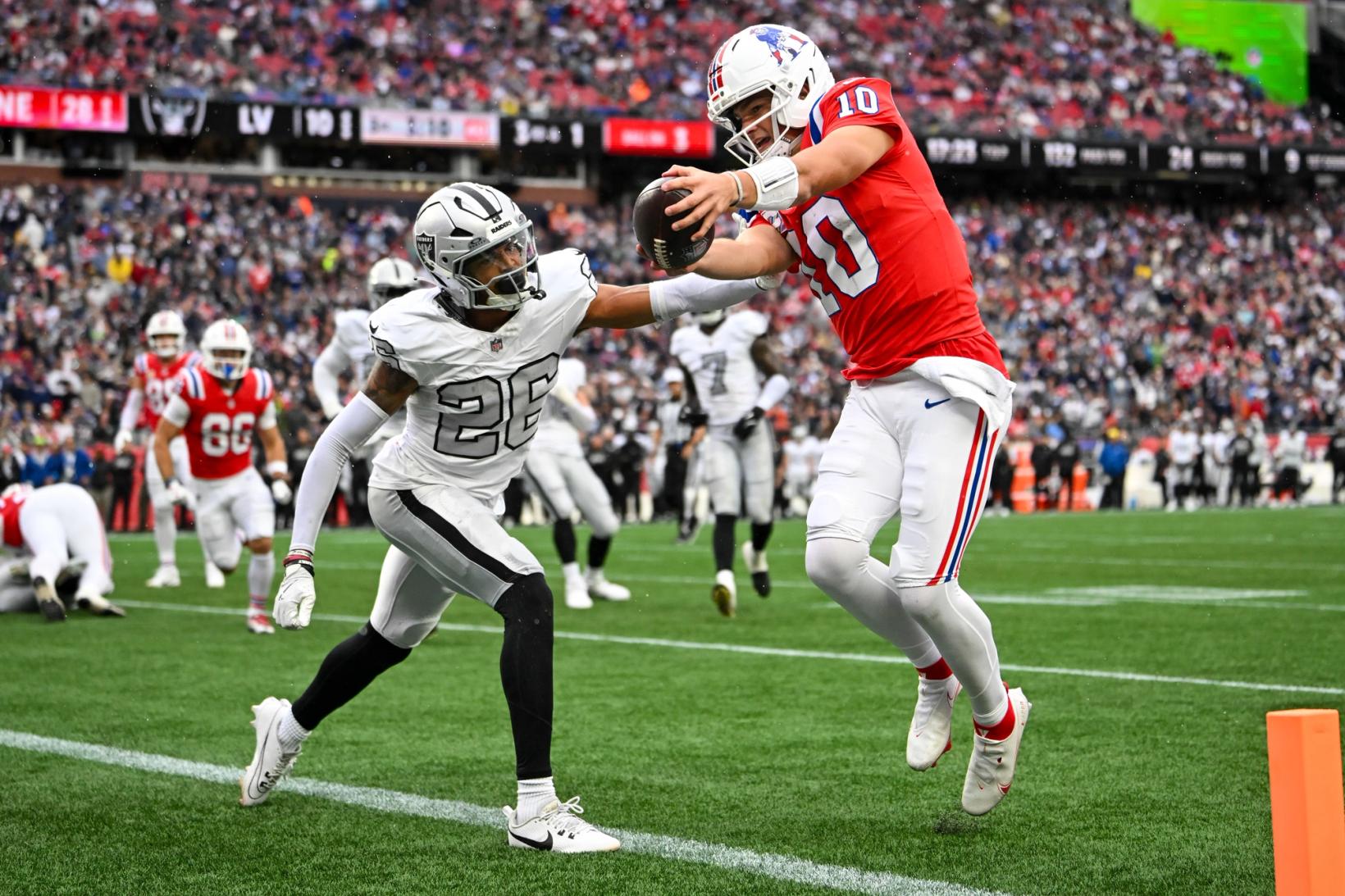 New England Patriots quarterback Drake Maye (10) reaches the ball toward the pylon as Las Vegas Raiders defender Darien Porter (26) closes in at Gillette Stadium.