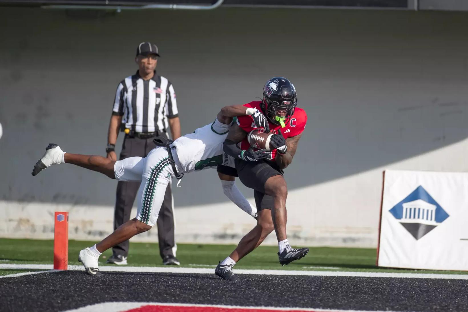 Northern Illinois receiver DeAree Rogers hauls in a pass in the end zone as a diving Hawai'i defender wraps him up during Hawai'i's 56-21 win at Huskie Stadium in DeKalb on October 24, 2026.