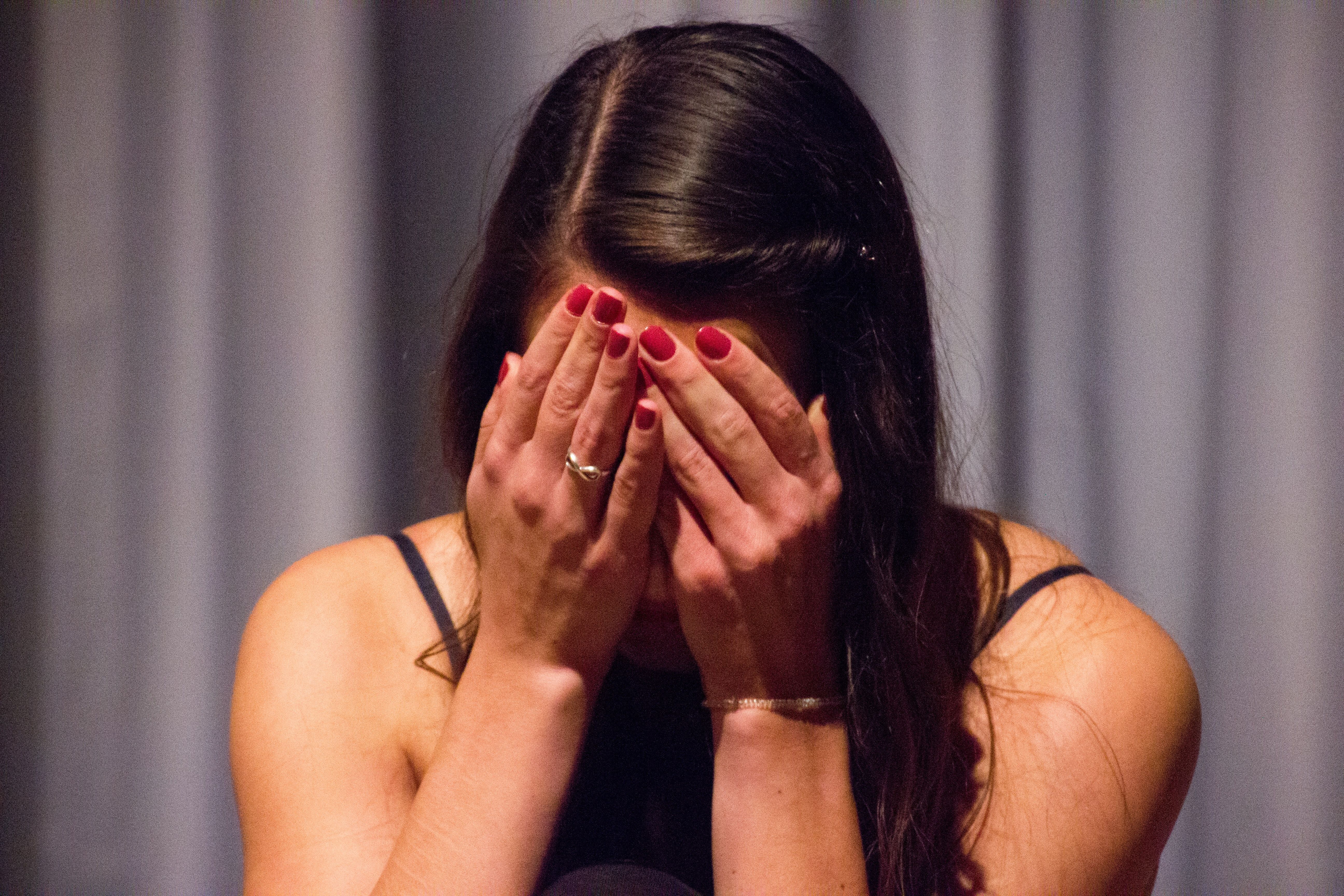 An embarassed woman holding her hands over her face