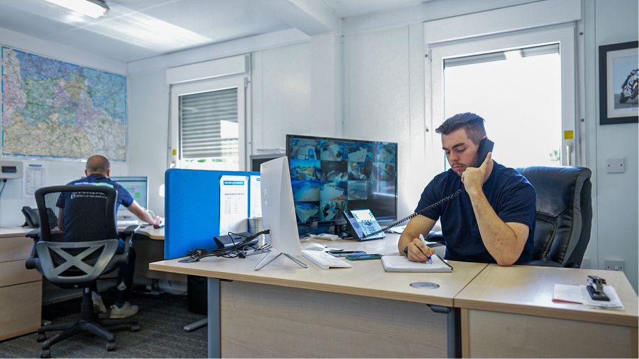 A construction worker holding a telephone in an office