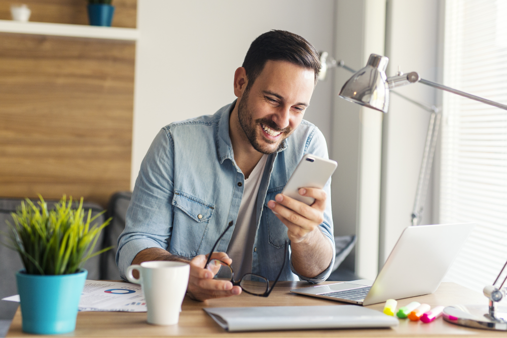 Young smiling freelancer reading message on his phone