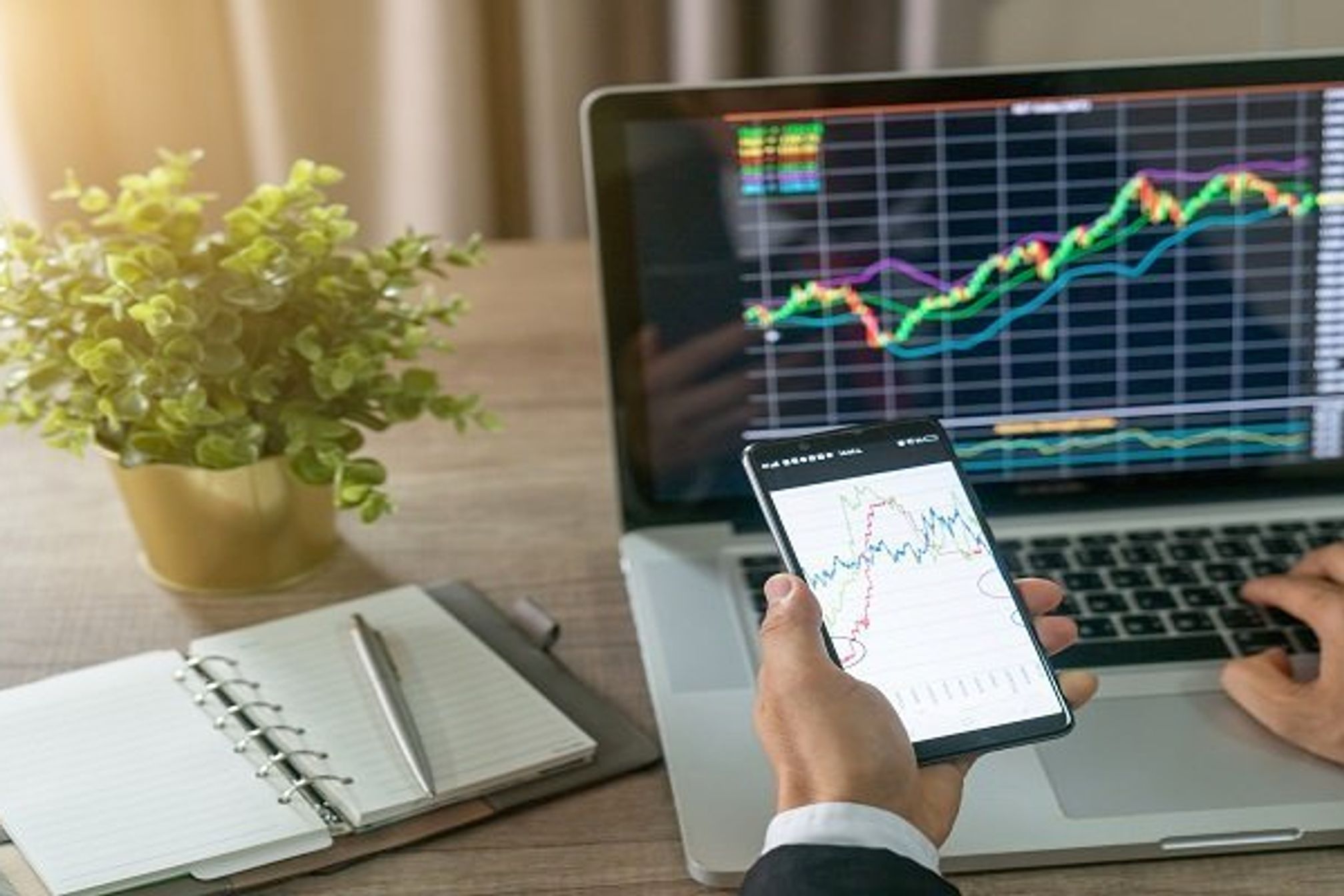 Investor analyzing stock market investments with financial dashboard, business intelligence (BI), and key performance indicators (KPI) on smartphone and computer screens