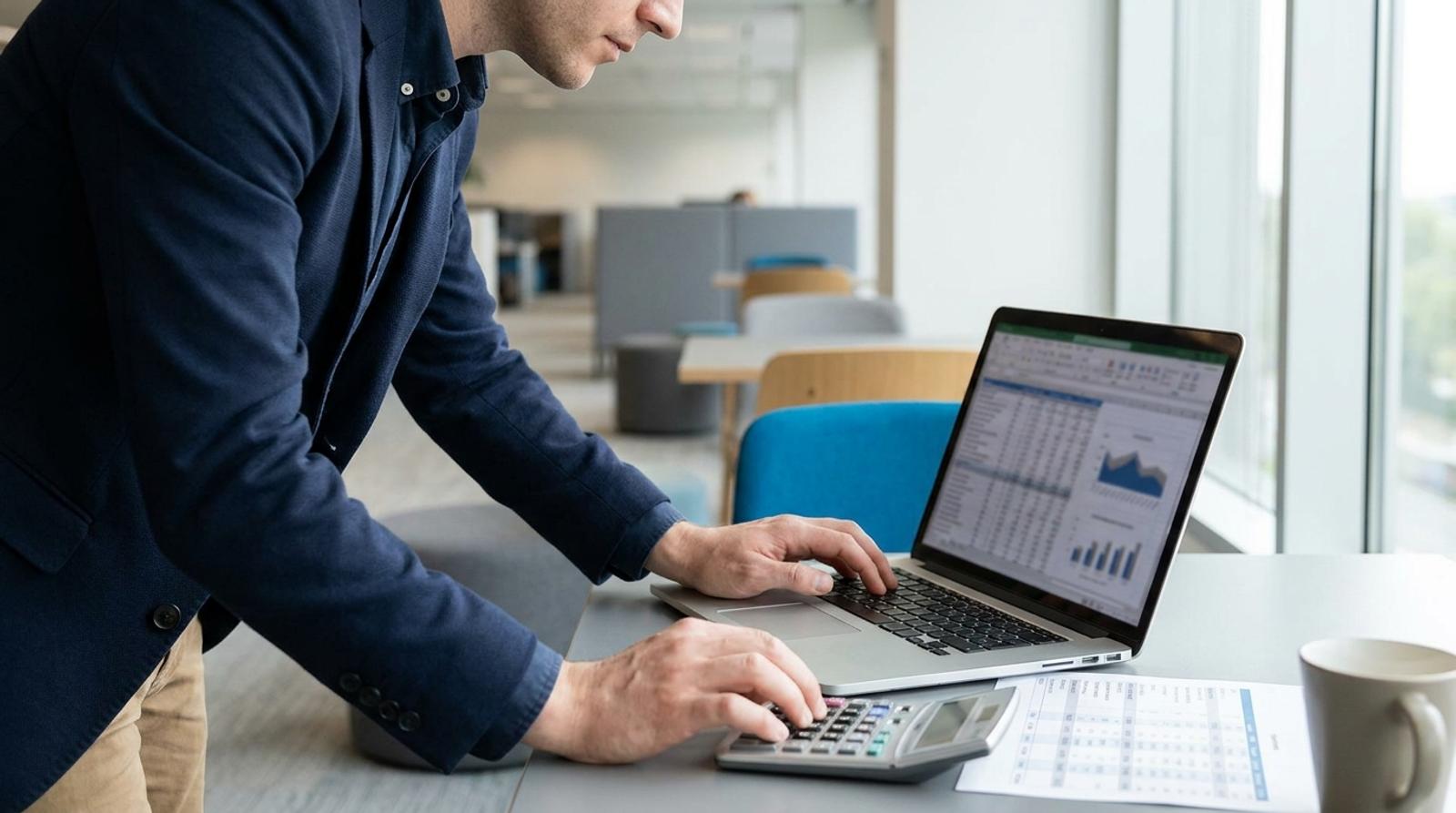 Procurement analyst reviewing a quote breakdown on a laptop with a calculator