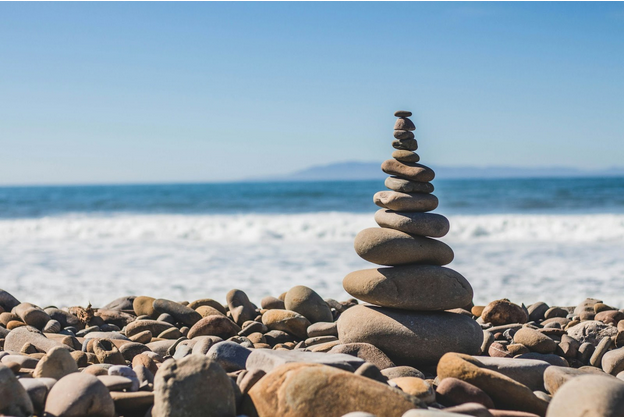 Stacked stones balanced on a rocky beach with calm ocean waves in the background