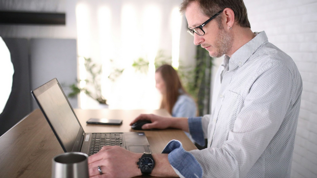 Two colleagues reviewing annotated documents side by side with laptops open during an RFP collaboration session