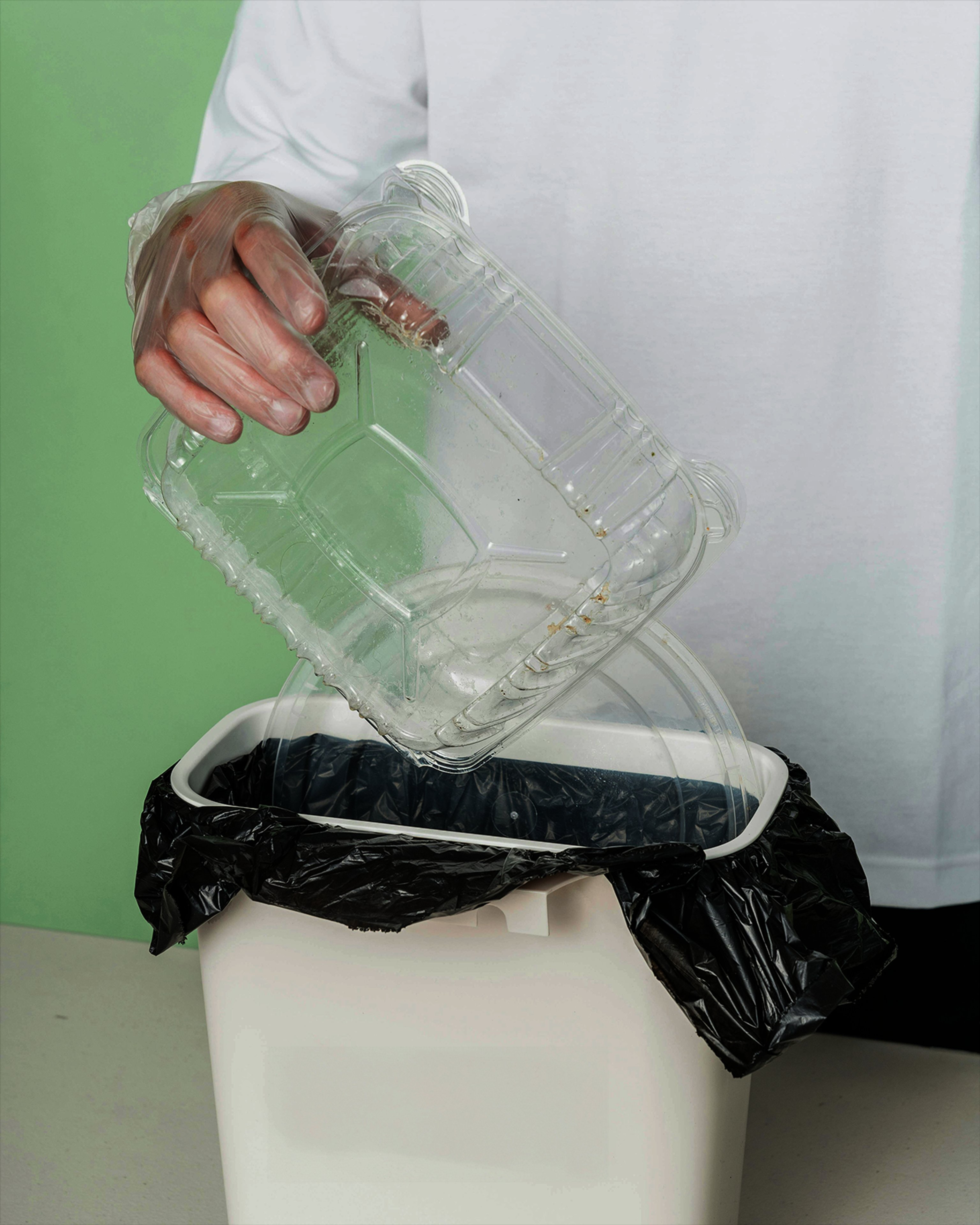 Image of a person putting plastic food packaging into a bin