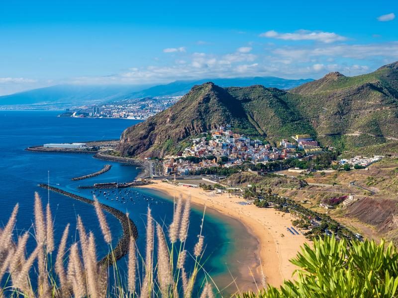 lage de sable doré et village côtier entourés de montagnes à Tenerife, îles Canaries.