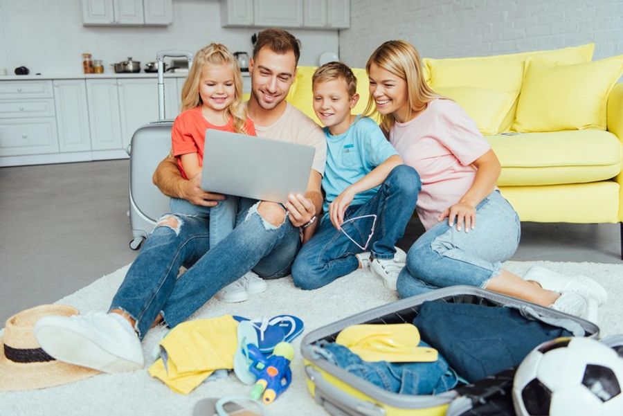 Famille préparant son voyage en van, souriante et réunie autour d’un ordinateur avant le départ.