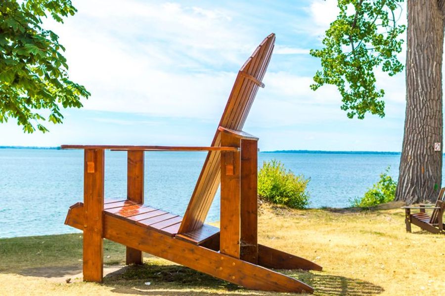 Une grande chaise Adirondack en bois au bord du lac Ontario, dans un parc de Kingston.
