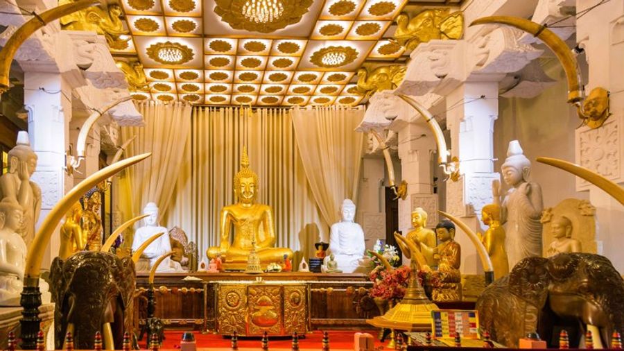 ntérieur du temple de la dent à Kandy, richement décoré de statues de Bouddha et d’ornements dorés.