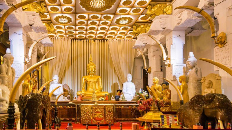 ntérieur du temple de la dent à Kandy, richement décoré de statues de Bouddha et d’ornements dorés.