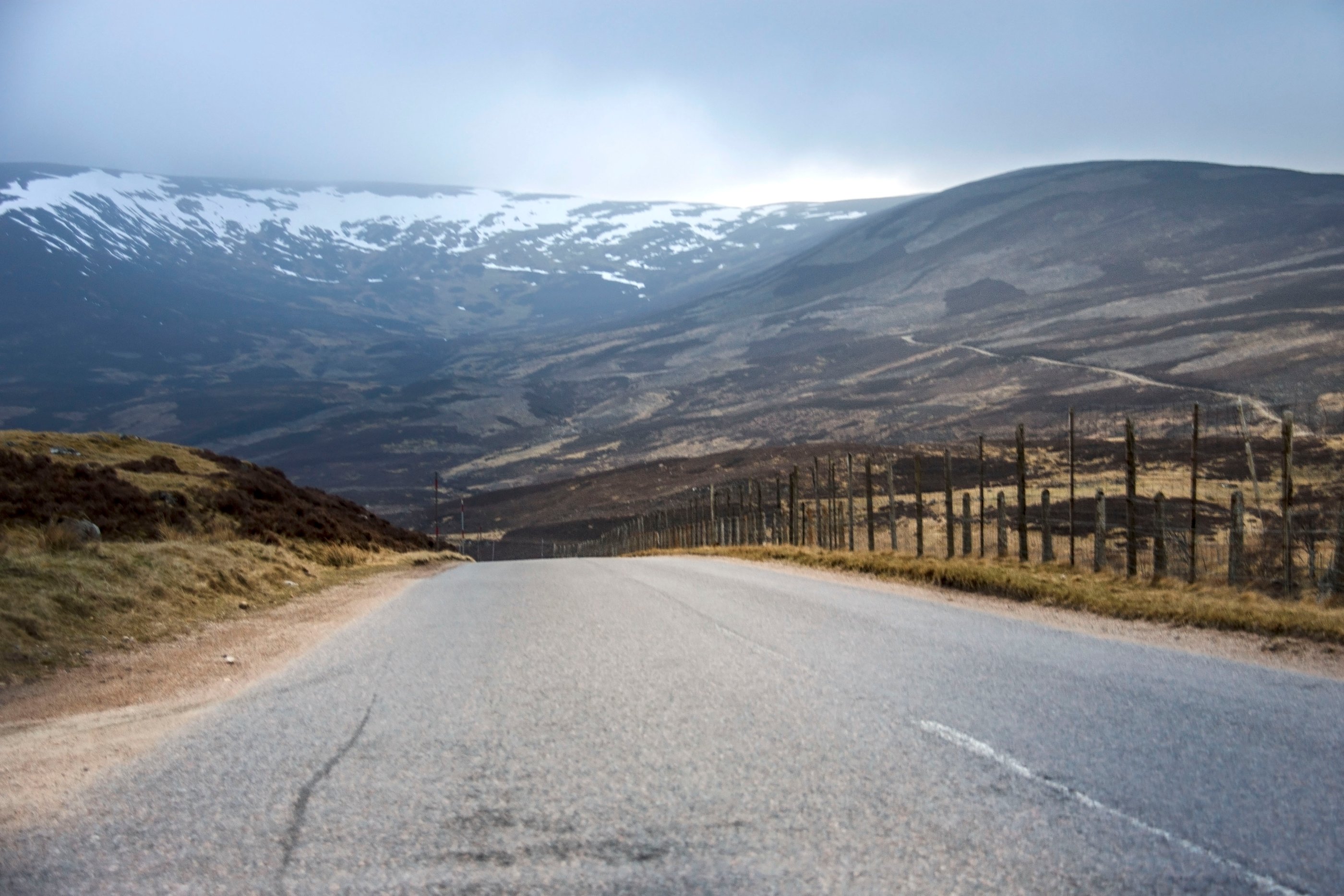 Route sinueuse dans les Highlands écossais, face à des montagnes