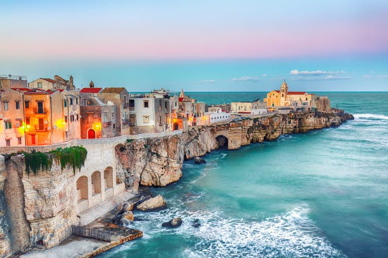 Vue pittoresque de Vieste dans les Pouilles, avec ses maisons colorées perchées sur une falaise au-dessus de la mer Adriatique au coucher du soleil.