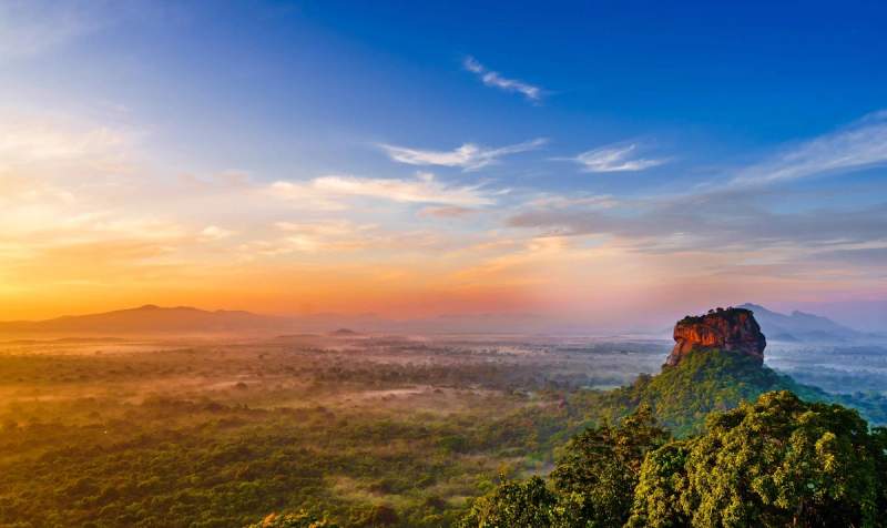 Vue panoramique sur le rocher de Sigiriya au lever du soleil, offrant un paysage spectaculaire sur la jungle sri lankaise.