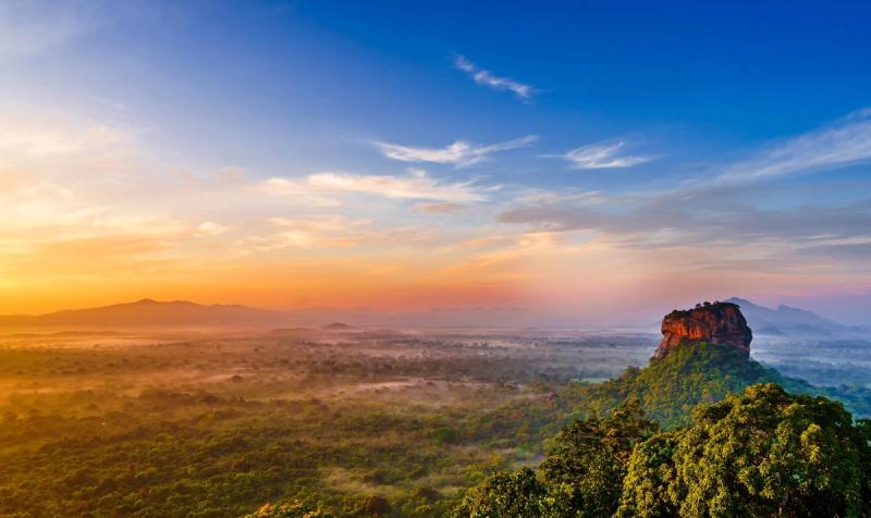 Vue panoramique sur le rocher de Sigiriya au lever du soleil, offrant un paysage spectaculaire sur la jungle sri lankaise.