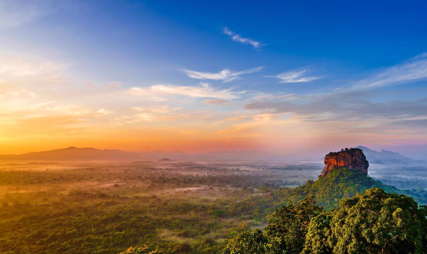 Vue panoramique sur le rocher de Sigiriya au lever du soleil, offrant un paysage spectaculaire sur la jungle sri lankaise.