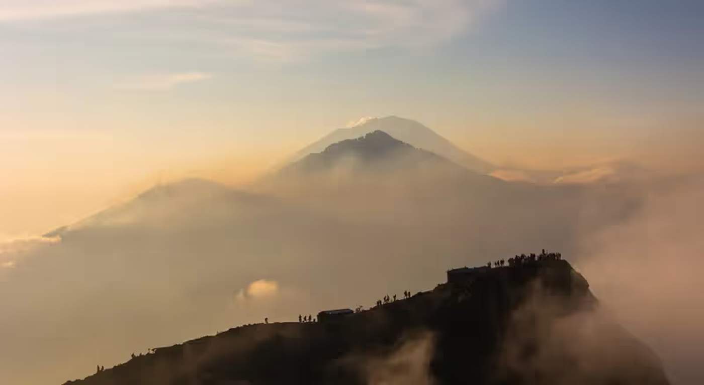 Randonneurs au sommet du Mont Batur admirant le lever du soleil au-dessus des nuages, Bali.