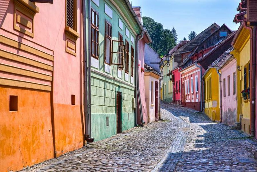 Rue pavée bordée de maisons colorées dans la citadelle médiévale de Sighisoara.