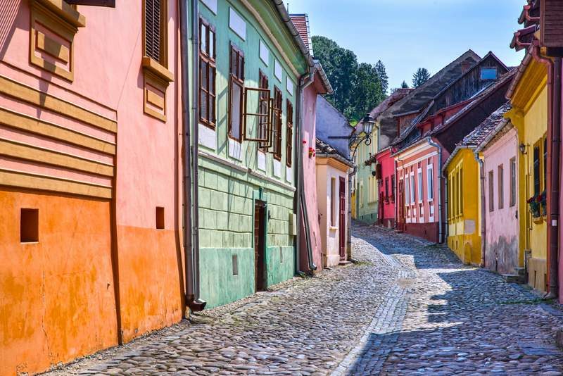 Rue pavée bordée de maisons colorées dans la citadelle médiévale de Sighisoara.