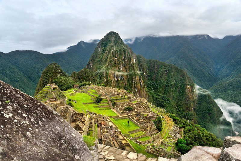Vue aérienne du site archéologique du Machu Picchu avec les terrasses incas et la montagne Huayna Picchu en arrière-plan.
