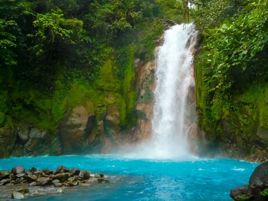 Cascade du Rio Celeste entourée de végétation tropicale luxuriante, avec une eau turquoise éclatante, située à Tamarindo au Costa Rica.