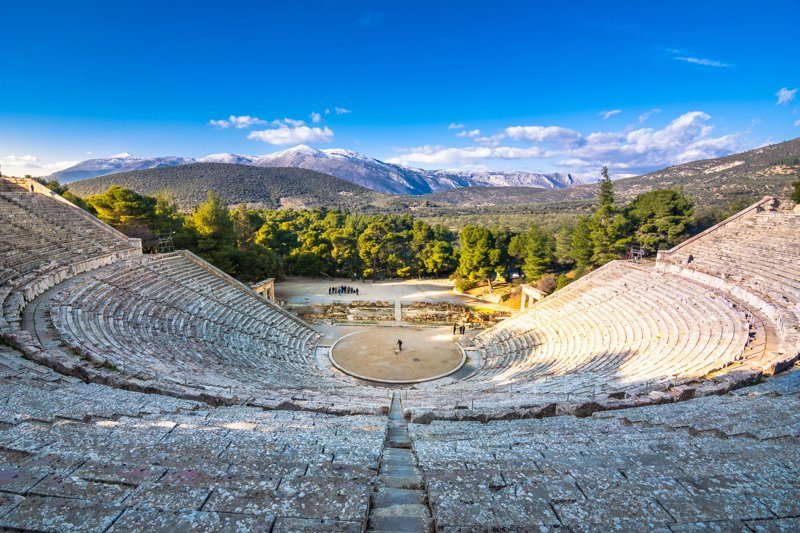 Vue spectaculaire du théâtre antique d’Épidaure, entouré de montagnes et de verdure.