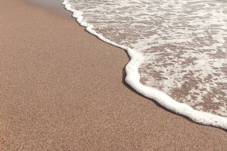 Plage de sable fin à Pals, avec des vagues douces venant caresser le rivage.