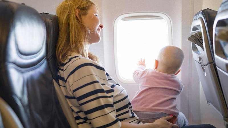 Maman tenant son bébé dans un avion, regardant par le hublot pendant le vol.