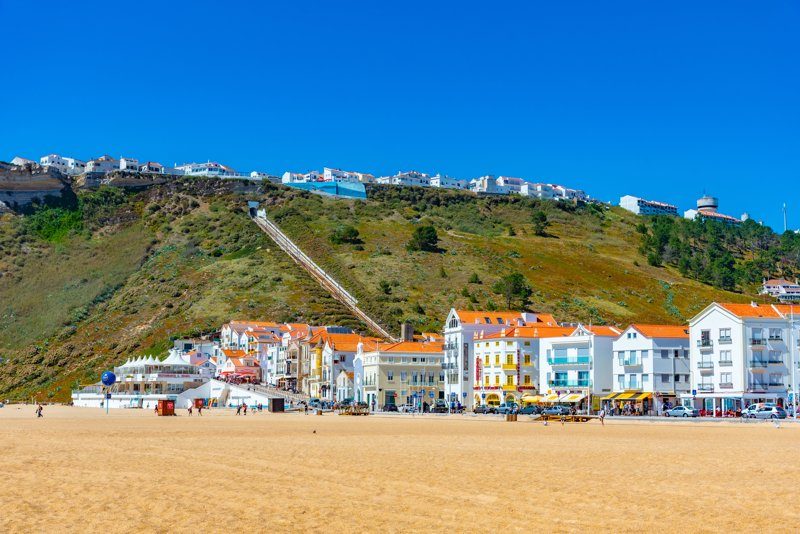 Vue sur les maisons traditionnelles du quartier de Pederneira à Nazaré, Portugal, surplombant la plage.