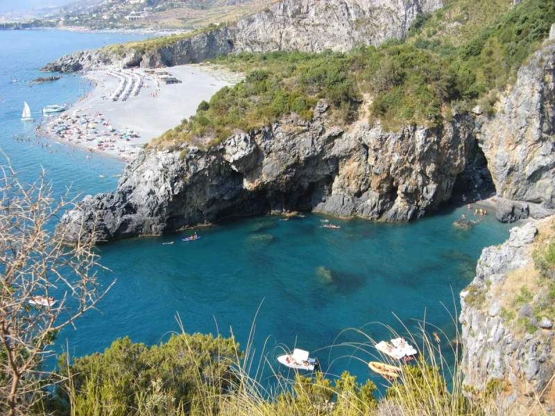 Vue aérienne d'une plage de la Calabre avec des falaises rocheuses et des eaux turquoise.