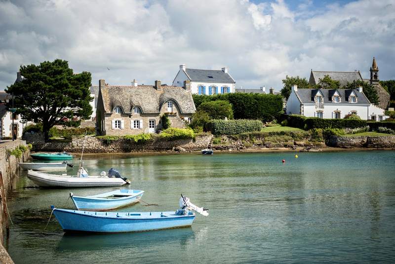 Vue pittoresque d’un petit port breton avec des barques colorées et des maisons traditionnelles en bord de mer.