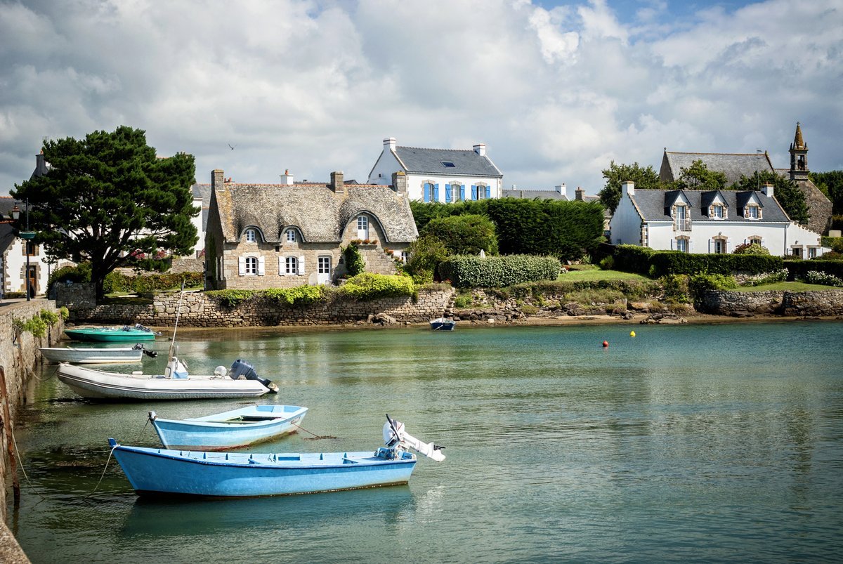 Vue pittoresque d’un petit port breton avec des barques colorées et des maisons traditionnelles en bord de mer.