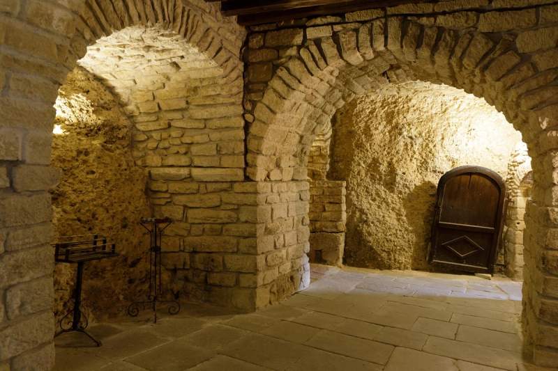 Intérieur d'une cave troglodytique en France, avec des murs en pierre calcaire et des arches voûtées, illustrant l'architecture traditionnelle de ces galeries souterraines historiques.