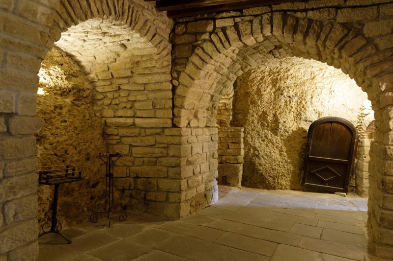 Intérieur d'une cave troglodytique en France, avec des murs en pierre calcaire et des arches voûtées, illustrant l'architecture traditionnelle de ces galeries souterraines historiques.