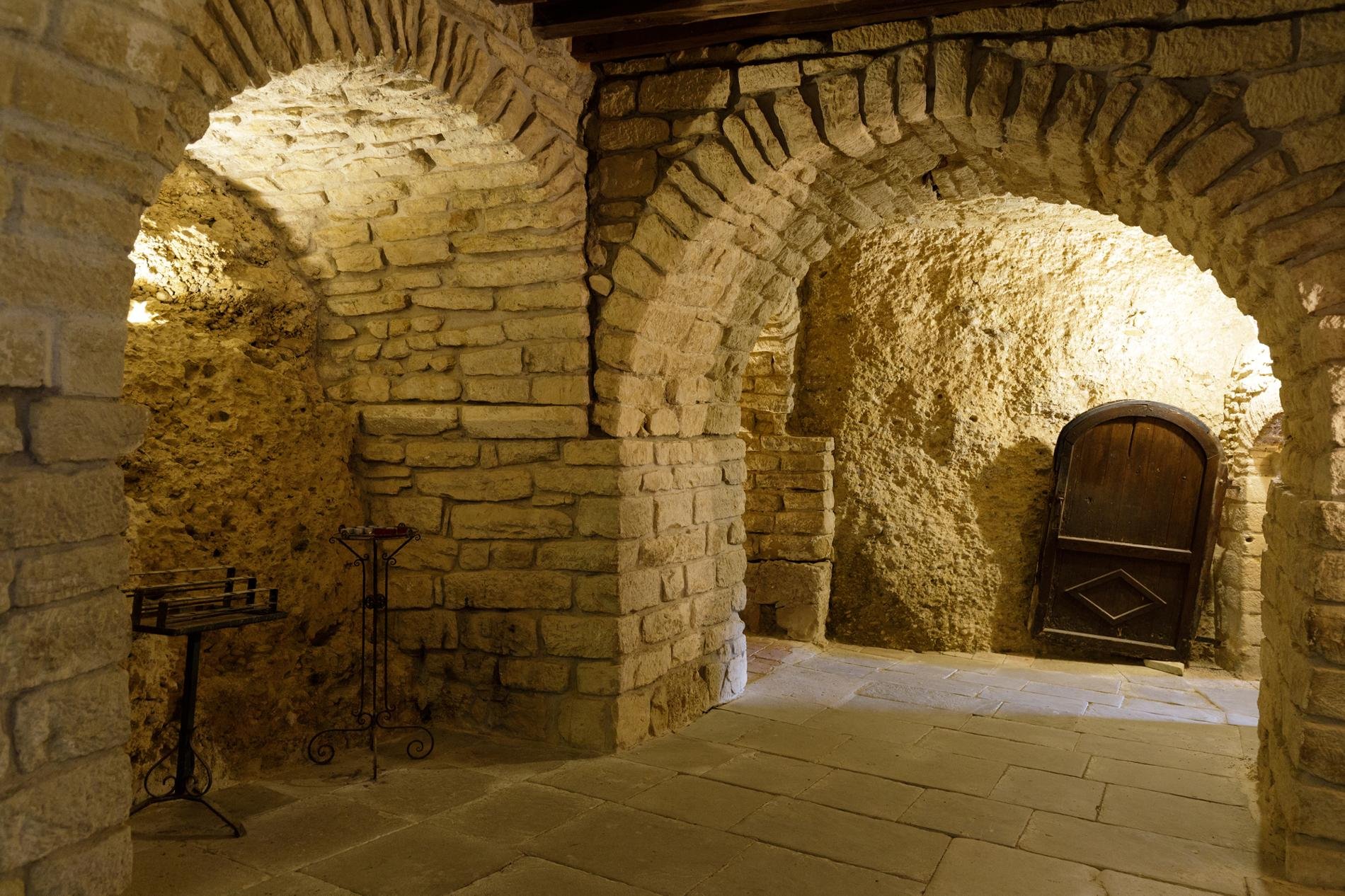 Intérieur d'une cave troglodytique en France, avec des murs en pierre calcaire et des arches voûtées, illustrant l'architecture traditionnelle de ces galeries souterraines historiques.