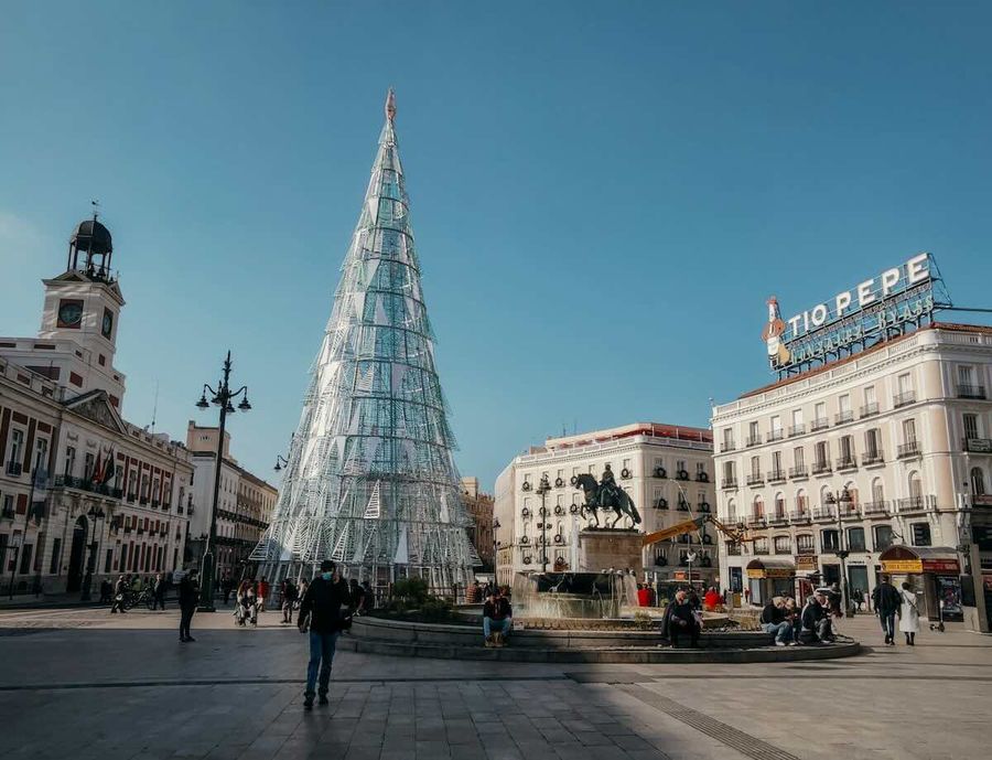 Plaza Puerta del Sol à Madrid avec un grand arbre de Noël, la statue équestre de Charles III, et le célèbre panneau lumineux "Tío Pepe".