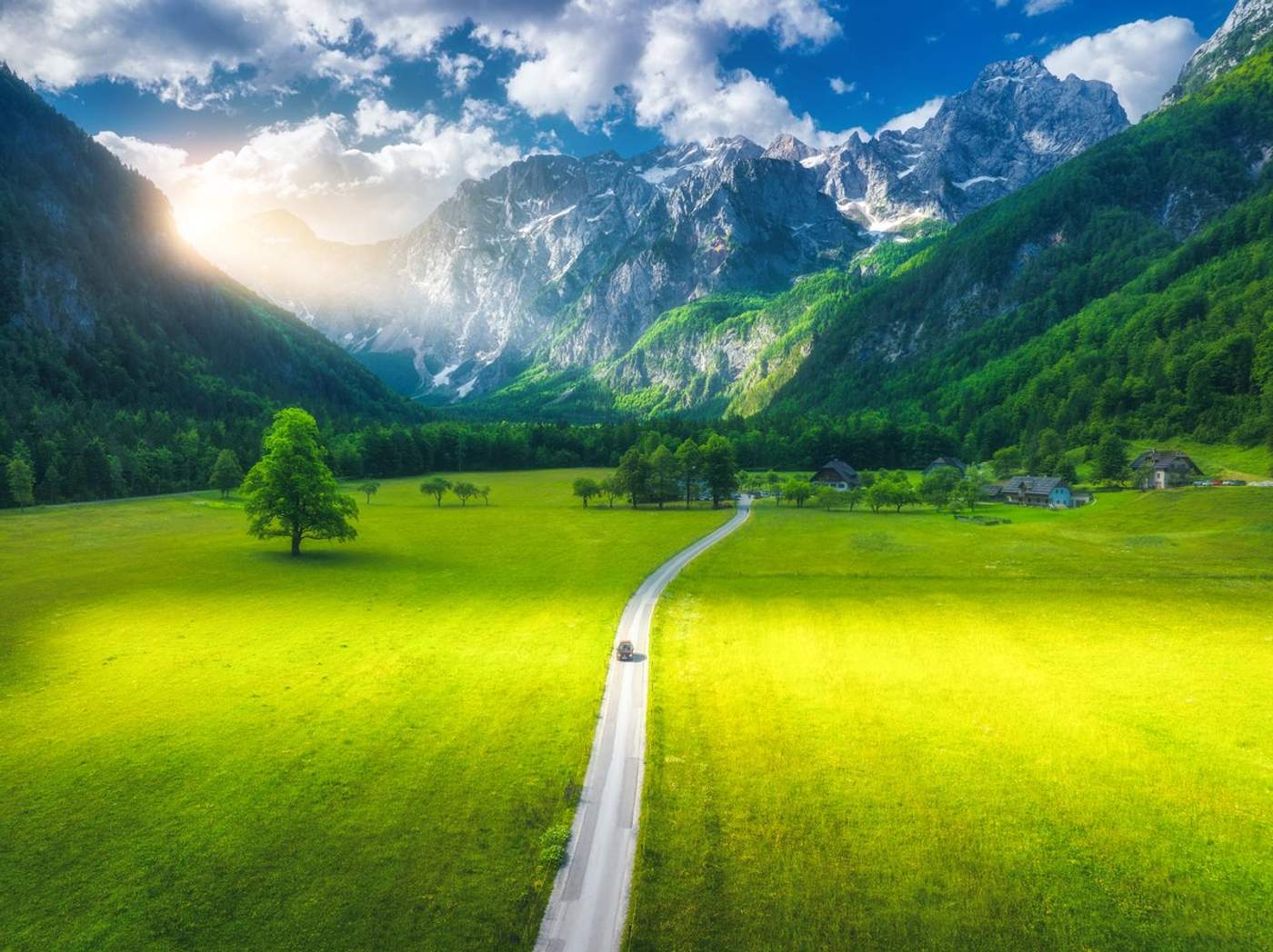 Vue aérienne de la route de la Logarska dolina (vallée de Logar) en Slovénie, traversant de vastes prairies verdoyantes encadrées par les sommets rocheux des Alpes Kamnik-Savinja