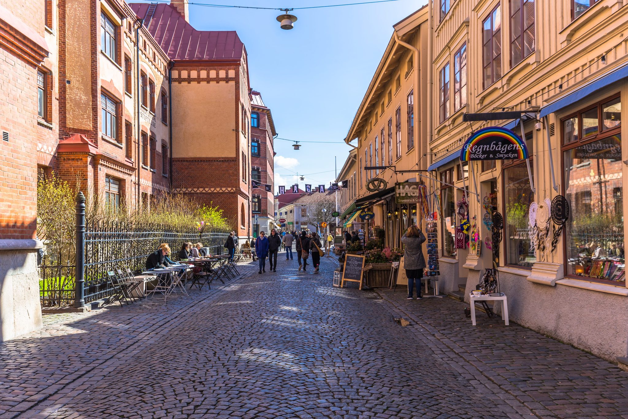 Rue pavée du quartier Haga à Göteborg, avec des commerces et des passants
