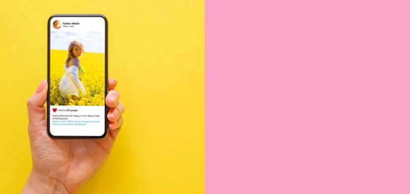 Une personne qui tient un smartphone sur un fond jaune et rose