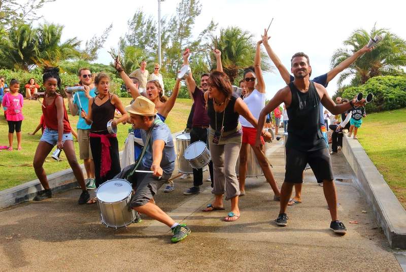 Groupe de musiciens et danseurs jouant des percussions lors d'un festival à La Réunion, en extérieur, avec une ambiance festive et conviviale.
