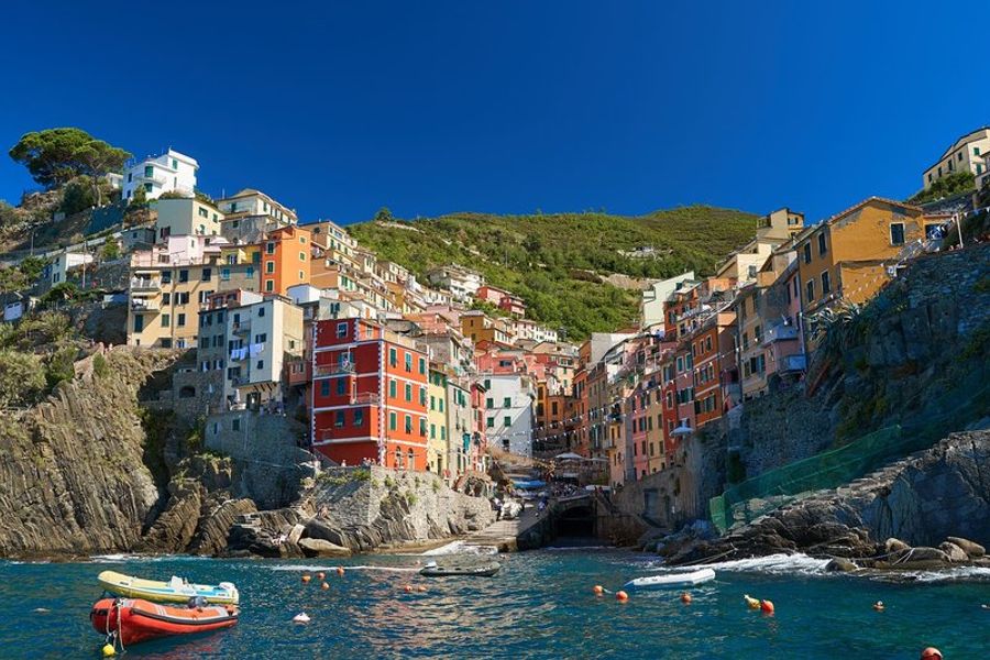 Le village coloré de Riomaggiore avec ses maisons en bord de mer et ses bateaux de pêche amarrés.
