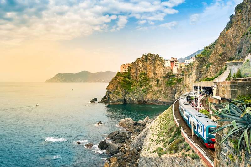 Un train régional bleu en gare de Manarola, village perché sur les falaises des Cinque Terre face à la mer Ligure au coucher du soleil